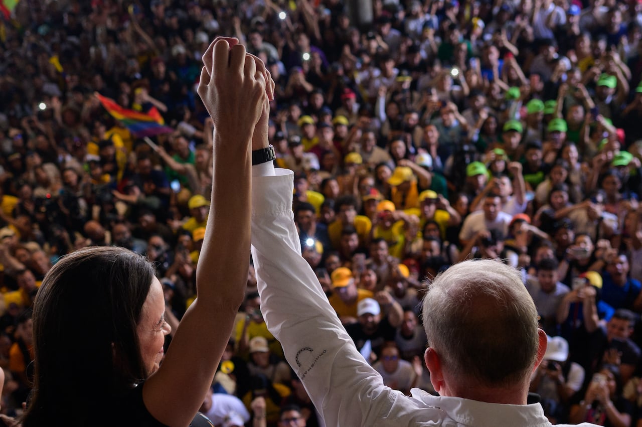 El candidato presidencial venezolano Edmundo González (R) y la líder de la oposición venezolana María Corina Machado saludan a estudiantes durante un mitin de campaña en la Universidad Central de Venezuela en Caracas el 14 de julio de 2024. (Foto de Gabriela Oraa / AFP)