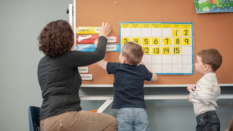 Profesora enseñando a estudiantes en los primeros años.